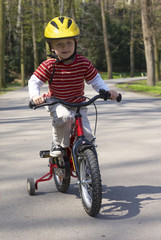 Fototapeta premium Young boy riding his first bicycle with training wheels 