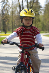 Naklejka premium Young boy riding his first bicycle with training wheels 