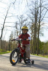 Young boy riding his first bicycle with training wheels 