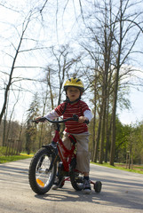 Obraz premium Young boy riding his first bicycle with training wheels 