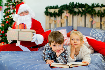 Fototapeta na wymiar Santa Claus quietly came to the children who are reading
