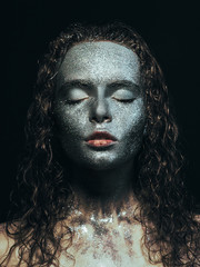 Girl in glitter Girl in glitter on her face with wet curly hair on black background Close-up