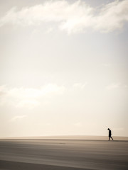 Solitary man walking through sand dunes, Lencois Maranhehses National Park, Brazil