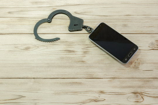 Phone connected to handcuffs fetters. concept of addiction dependence