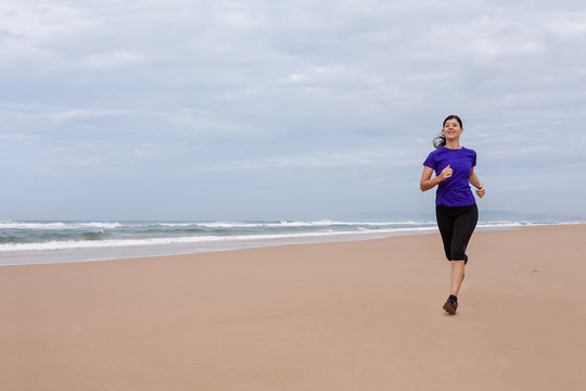 Female athlete running at the beach on an Autumn day.