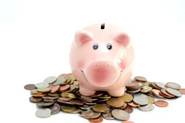 Pink piggy bank standing on coins, suggesting money savings concept