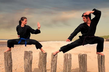 Foto auf Acrylglas Kampfkunst Zwei Kampfsportler praktizieren Kampfsport an den Strandstangen: Mann und Frau beim Karate - Viet Vo Dao Haltung
