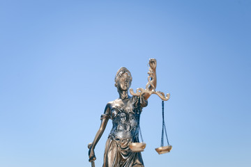 Sculpture of justice or themis goddess on outdoors bright blue sky background