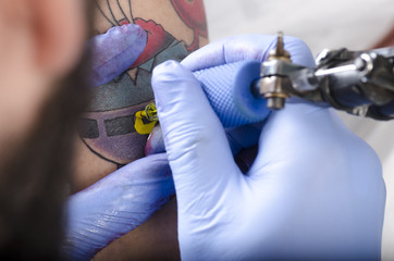 Professional tattooer burning the tatoo with gloves on by special tool closeup. Tattooer showing process of making a tattoo.