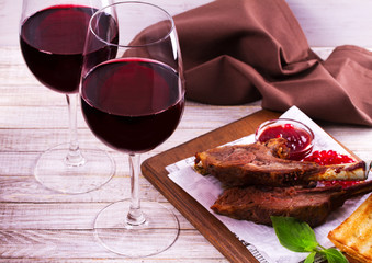 Red wine bottle and glasses. Wine and food still life. Rack of lamb with pomegranate sauce and greens
