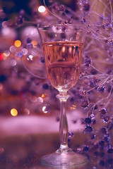 festive atmosphere in the evening with a glass of champagne and a rainbow colored bokeh. Dark background with multi-colored beautiful slices. Christmas, New Year's atmosphere.
