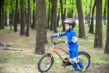 Fototapeta na wymiar Happy kid boy of 4 years having fun in autumn or summer forest with a bicycle