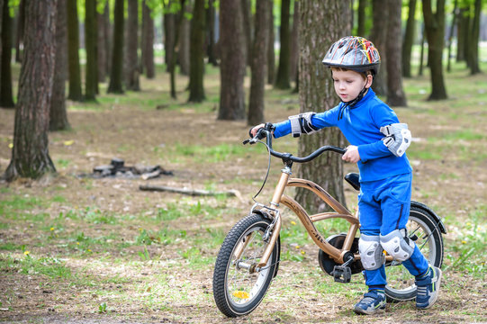 Happy kid boy of 4 years having fun in autumn forest with a bicycle on beautiful fall day. Active child making sports. Safety, leisure kids concept