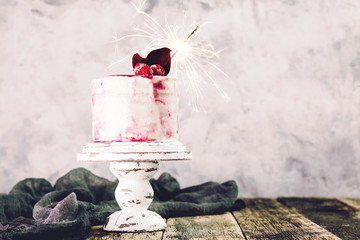 Birthday cake with sparkler on wooden vintage table