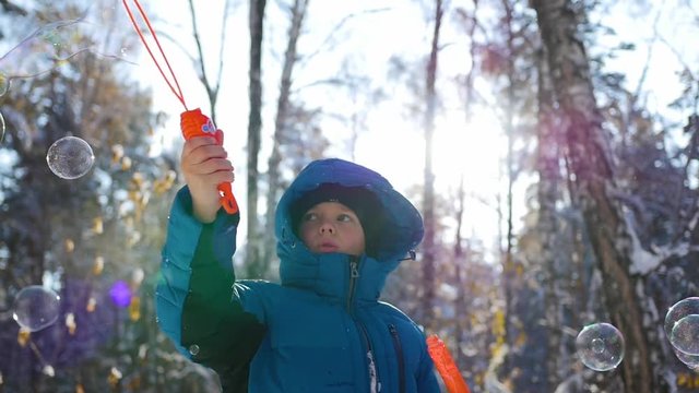 boy makes big soap bubbles in the Park with delight on a Sunny day