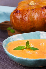 Bowl of pumpkin soup and  whole pumpkin. Butternut squash cream soup