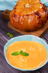 Bowl of pumpkin soup and  whole pumpkin. Butternut squash cream soup