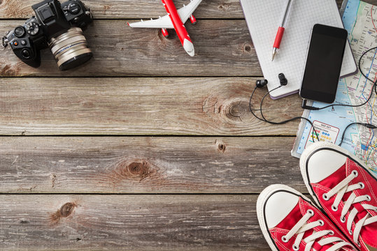 travel accessories: camera, map, phone with headphones, red sneakers on wood background. Travelling concept image