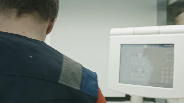 Poligraphy industry - worker use high tech monitor for printed process, rear view