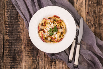 Tagliatelle with bacon cream sauce and mushrooms on wooden table