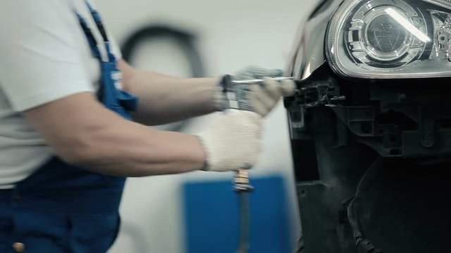 The worker unscrews the screws from the bumper.