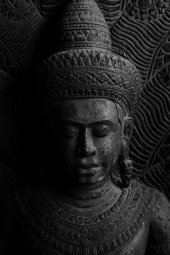 Dvaravati Buddha sculpture engrave from stone a style of Buddha with a Naga over His head by black and white photography