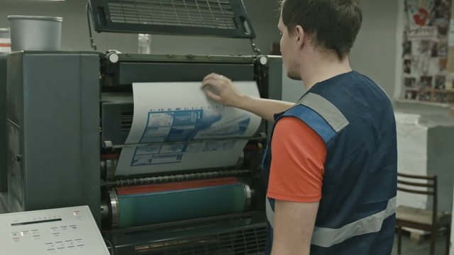 Worker pulls on the blank printable on polygraph industry process, color printing