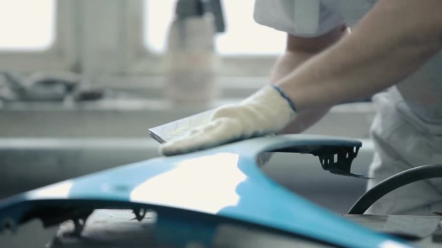 The worker polishes the surface of the bumper.