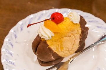 Chocolate cream puff with peach and cherry topping