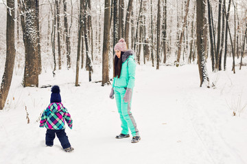 Fototapeta na wymiar happy mother and baby in winter park. family outdoors. cheerful mommy with her child