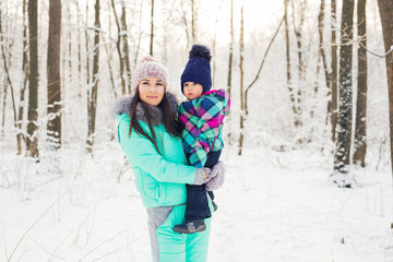 happy family mother and baby girl daughter playing and laughing in winter outdoors in the snow.