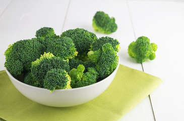 Raw broccoli in bowl on white table
