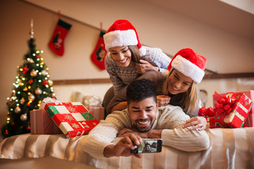 Fototapeta na wymiar Cheerful friends taking a Christmas selfie with smartphone.