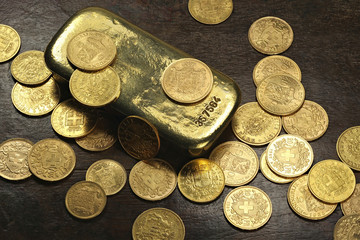 Goldbarren mit verschiedenen europäischen Goldmünzen aus dem 19./20. Jahrhundert auf rustikalem...