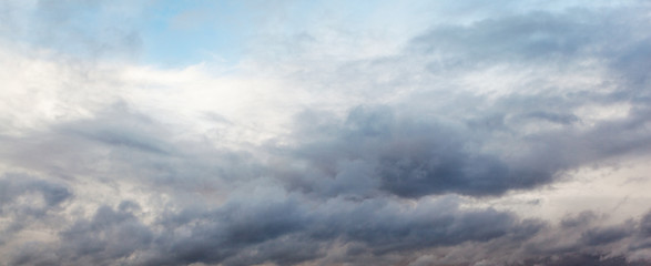 Obraz premium Beautiful dramatic sky with gray clouds and sunset. Dark blue feather shaped clouds in the background of bright orange sunset.