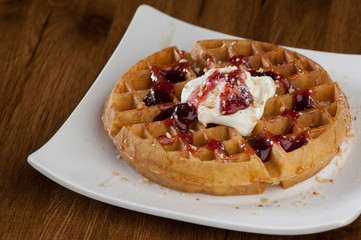 Wafer cake in a square white plate on a wooden lacquered surface with reflection