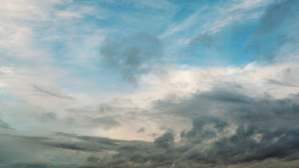 Beautiful dramatic sky with gray clouds and sunset. Dark blue feather shaped clouds in the background of bright orange sunset.