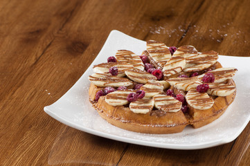 Wafer cake in a square white plate on a wooden lacquered surface with reflection