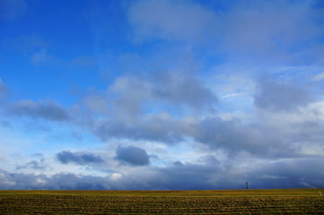 grau blauer Wolkenhimmel über winterlich kahlen Feldern
