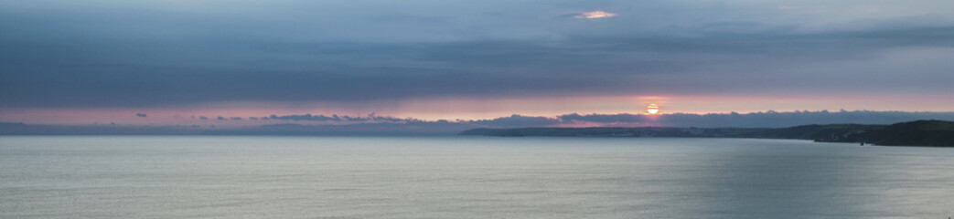 Very long & thin panorama of sunset over ocean.