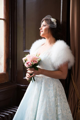 Happy and content bride leans against wall looking out the windo