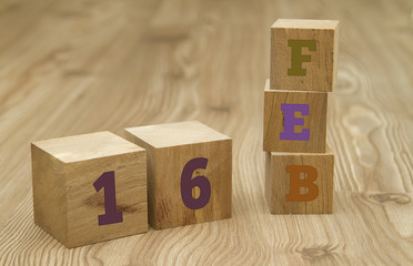 Cube shape calendar for February 16 on wooden surface.