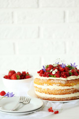 Delicious biscuit cake with berries on white wooden table