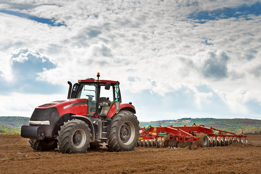 modern red tractor in the agricultural field.