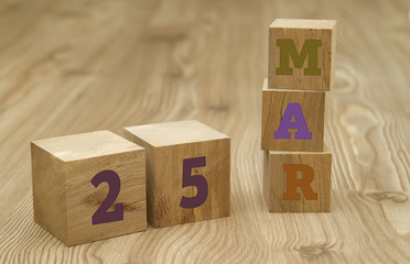 Cube shape calendar for March 25 on wooden surface.