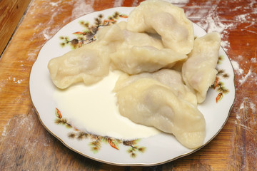 Delicious dumplings with cherries, sour cream in plate.