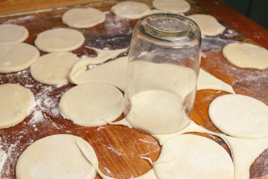 Making ukrainian dumplings or varenyky, cutting with a glass the round pieces of dough