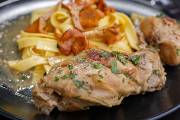 Braised rabbit with Italian pasta tagliatelle and Gérin chanterelles mushrooms on a black plate. homemade food
