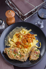 Tagliatelle with chanterelles and stewed rabbit on black terelke. side and top view. Italian pasta homemade food. setout