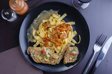 Tagliatelle with chanterelles and stewed rabbit on black terelke. side and top view. Italian pasta homemade food. setout